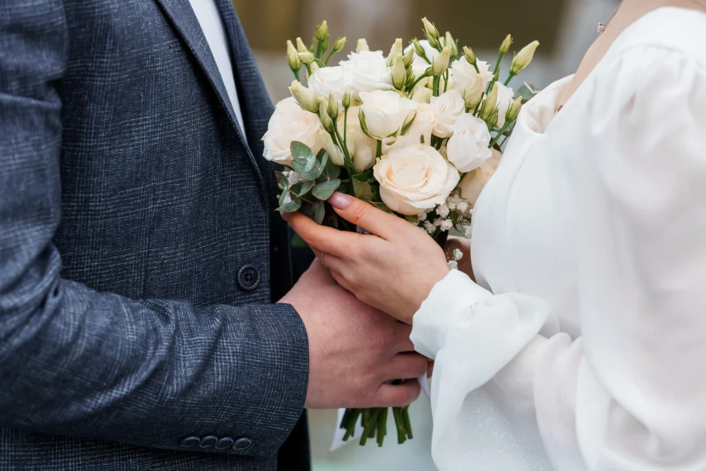 Close up of bride and groom's hands both holding flower bouquet at wedding | Are Wedding Loans a Good Idea?