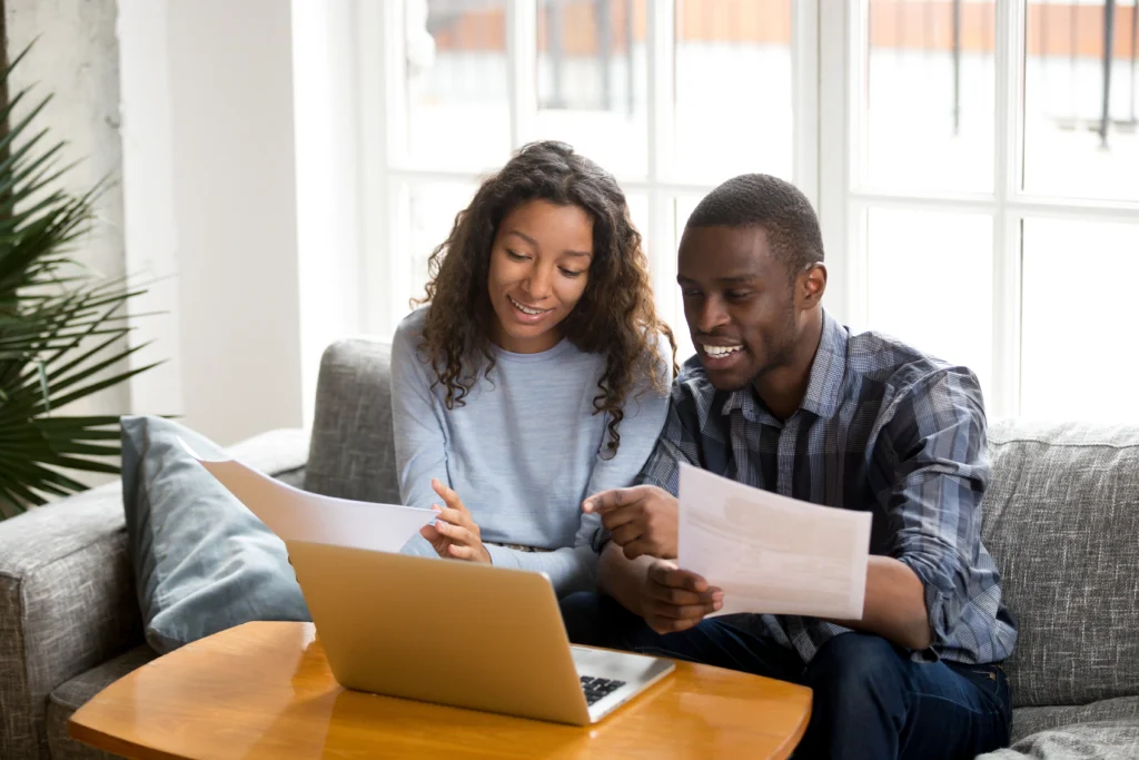 Couple holding documents and looking at laptop doing financial planning