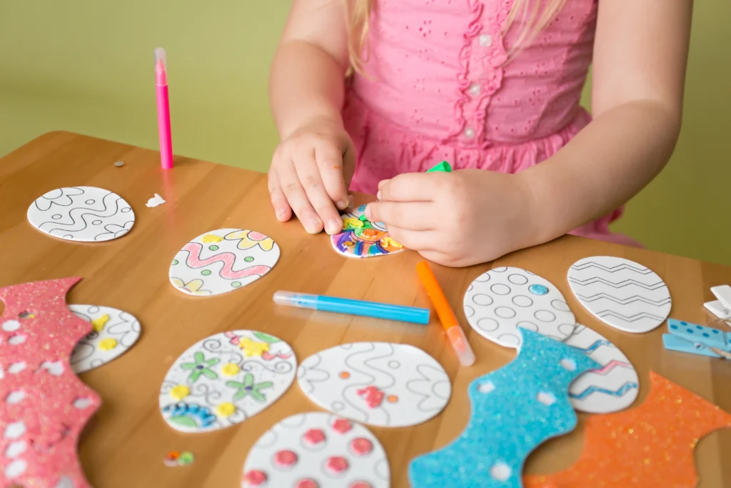 Close up of a child's hands while they colour in paper Easter eggs