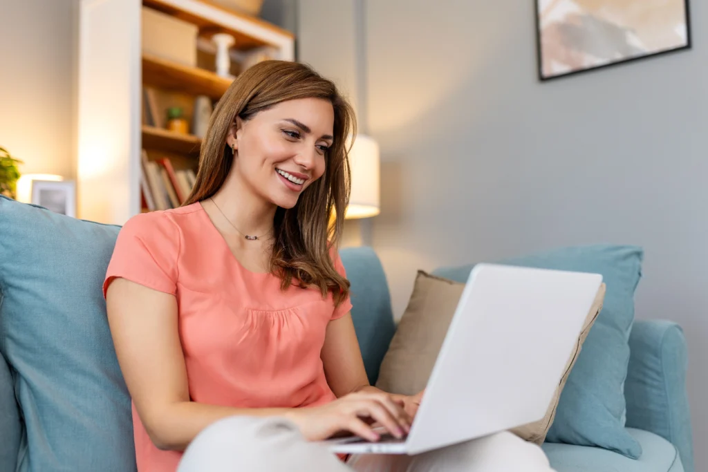 Woman smiles at her laptop researching how to get instant approval for a personal loan