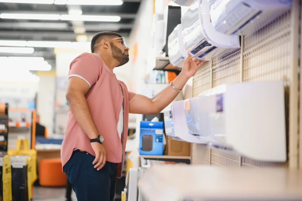 Man in an appliance store inspects various air conditioning units