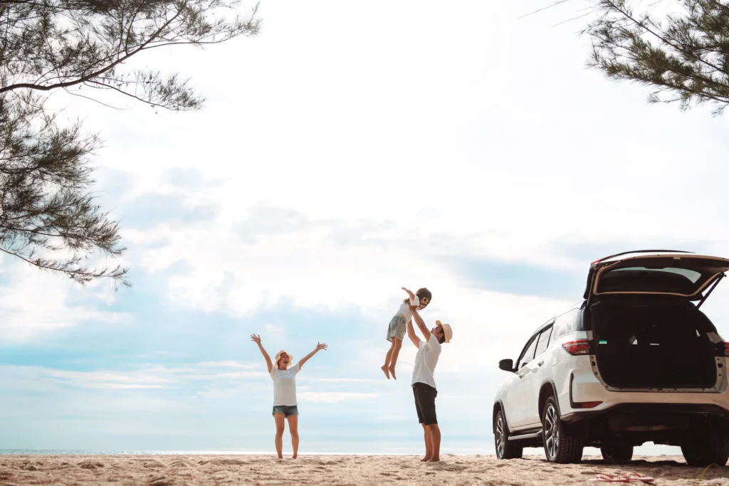 Young parents and their child celebrating a successful Labour Day road trip to a Queensland beach