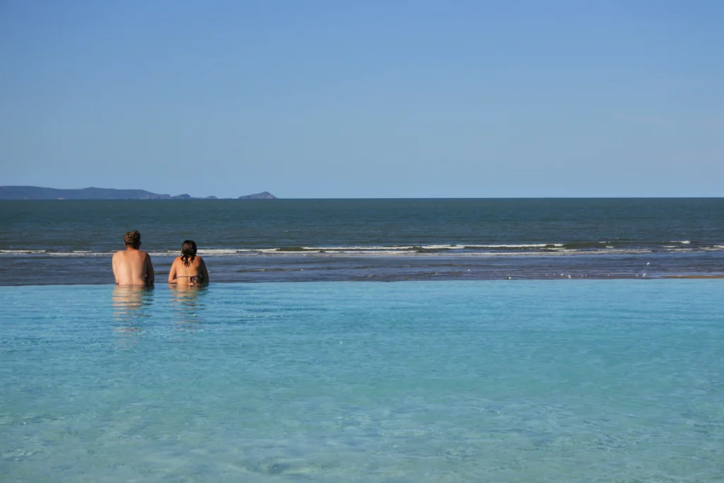 A couple look out to sea from the infinity pool in Yeppoon