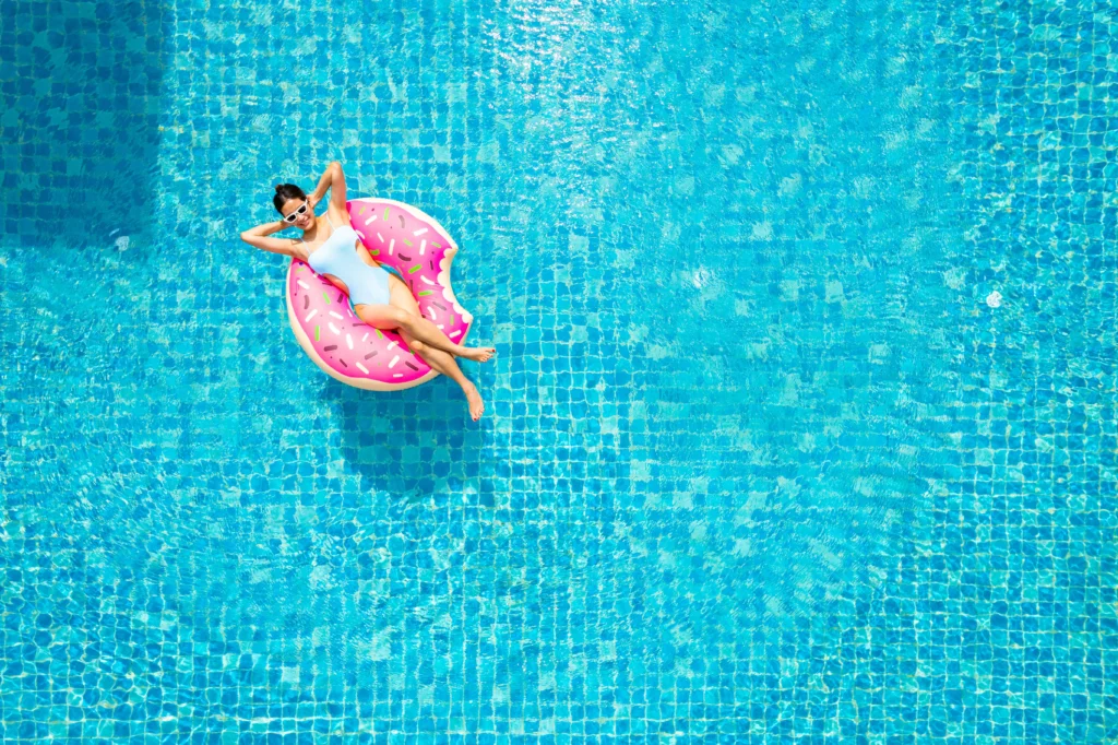 Happy woman on an inflatable donut in the middle of a pool after figuring out how much will it cost to build a pool