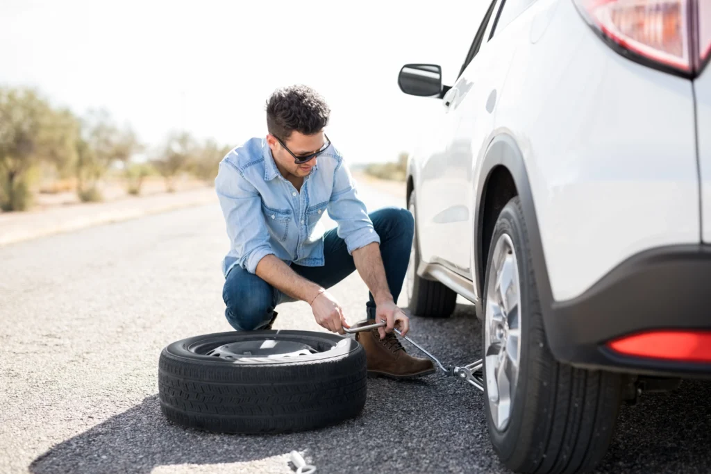 Man changing a tyre on the side of a road